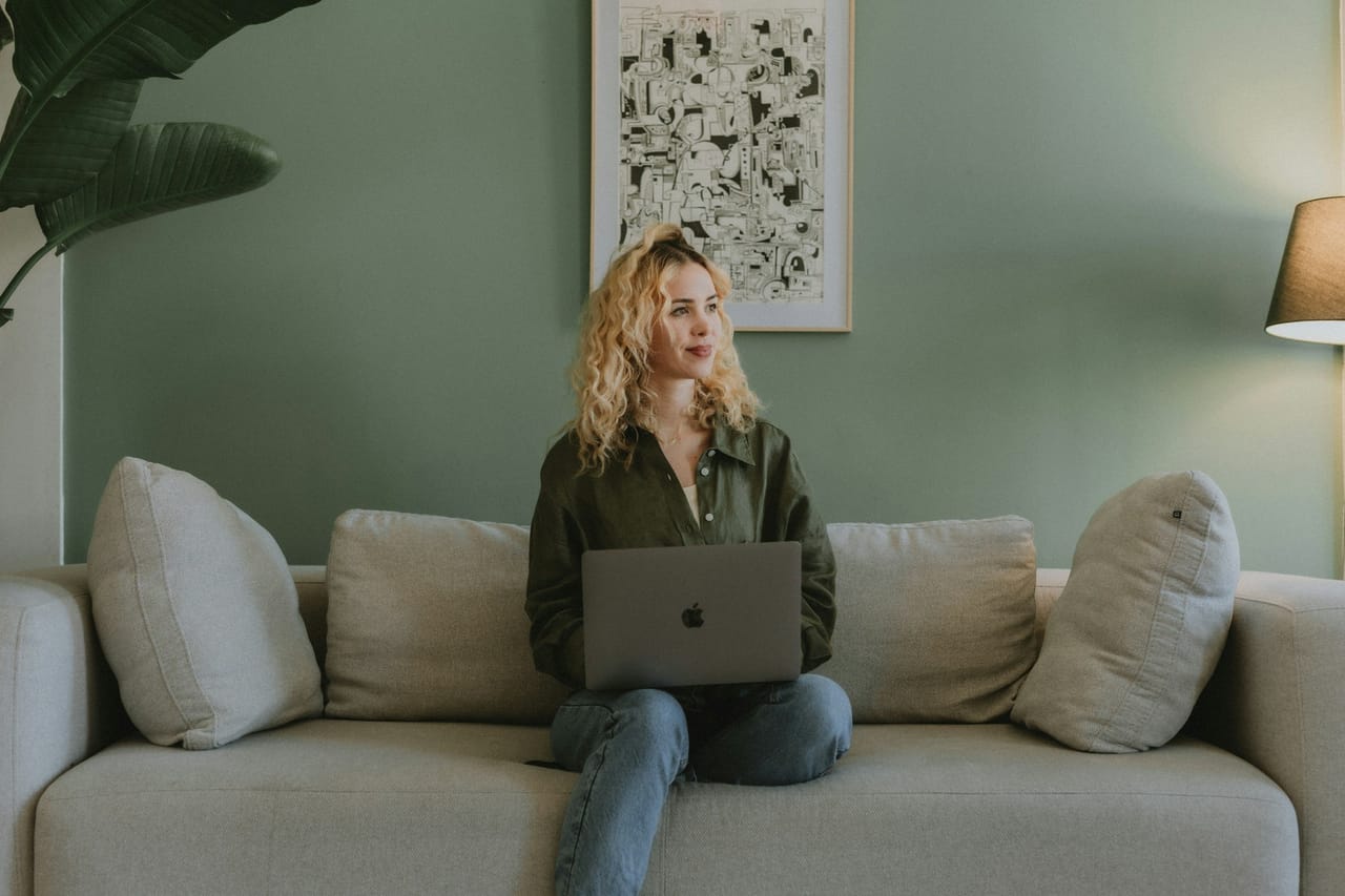 A woman on a sofa at home with a laptop on her knees
